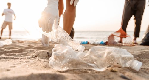 Group of young friends volunteers cleaning beach from plastic garbage