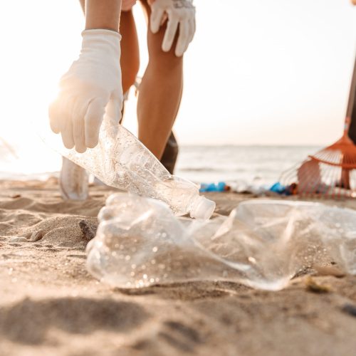 Group of young friends volunteers cleaning beach from plastic garbage